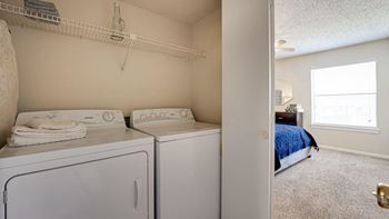 a bedroom with a washer and dryer at Woodland Hills Apartments in Irving, Texas